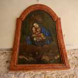 Con Ges� tra le braccia, tiene in mano lo scapolare: due rettangolini di stoffa raffiguranti Maria con il bambino e il cuore di Cristo. Sotto il mezzobusto, delle anime tra le fiamme del Purgatorio si rivolgono a lei
